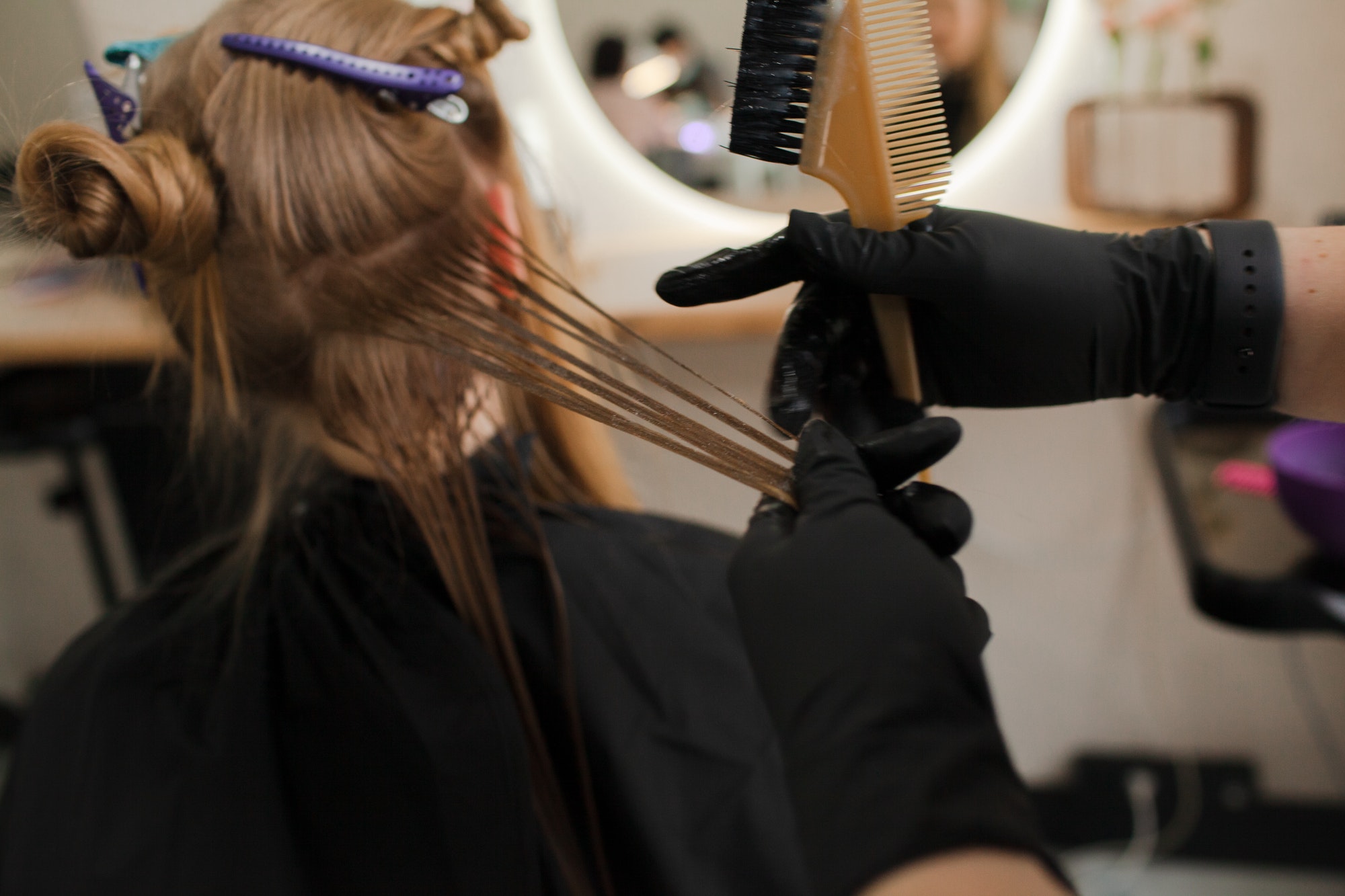 The hairdresser paints or makes keratin to a girl in a professional salon
